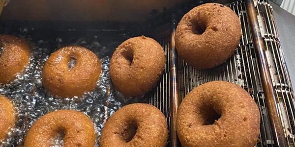 Apple cider donuts moving through Meadow Ledge Farm’s fryer, photographed for Visit NH